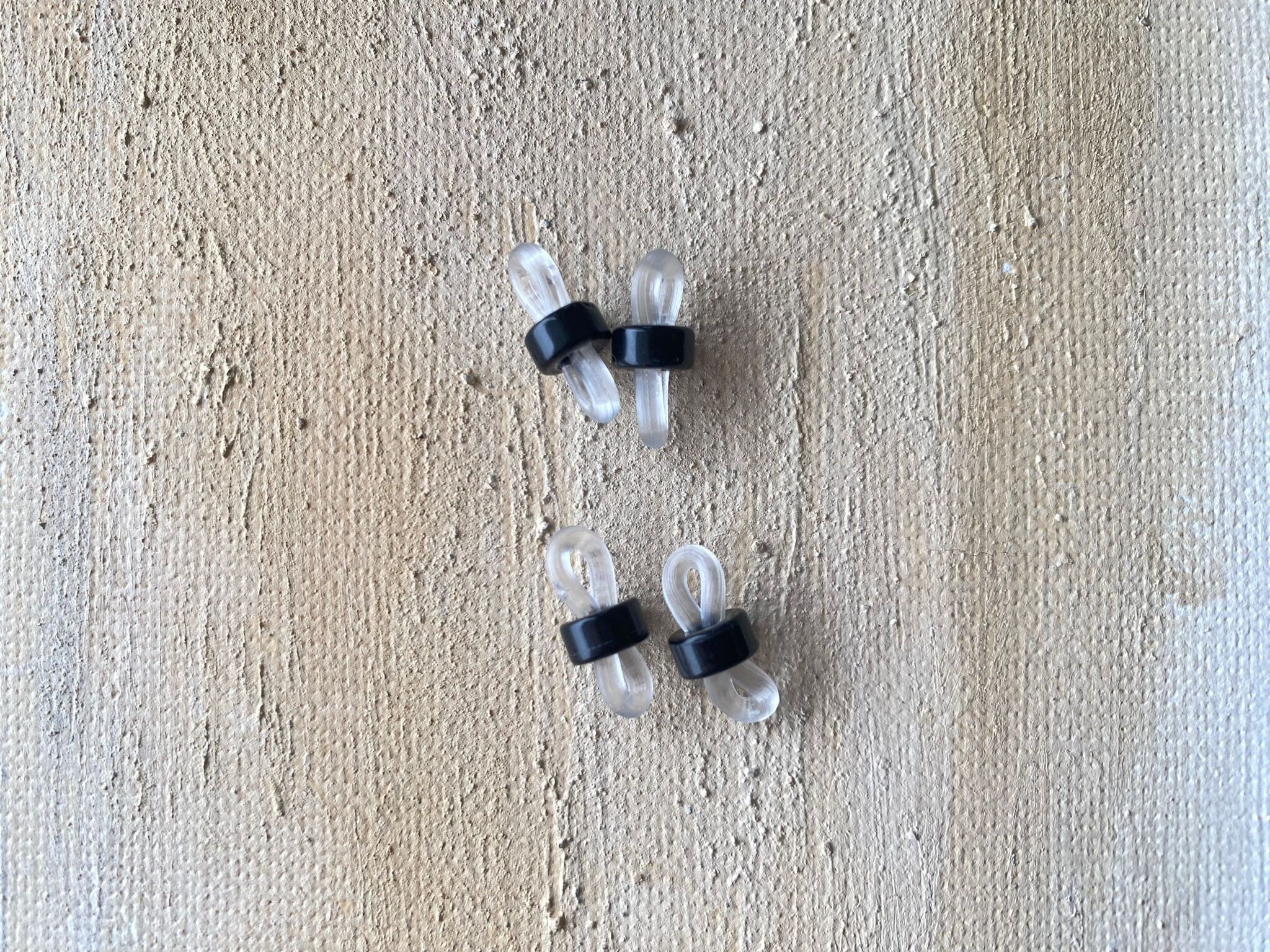 May include: Four clear plastic eyeglass holders with black rubber bands. The holders are designed to keep glasses from sliding down or dropping.