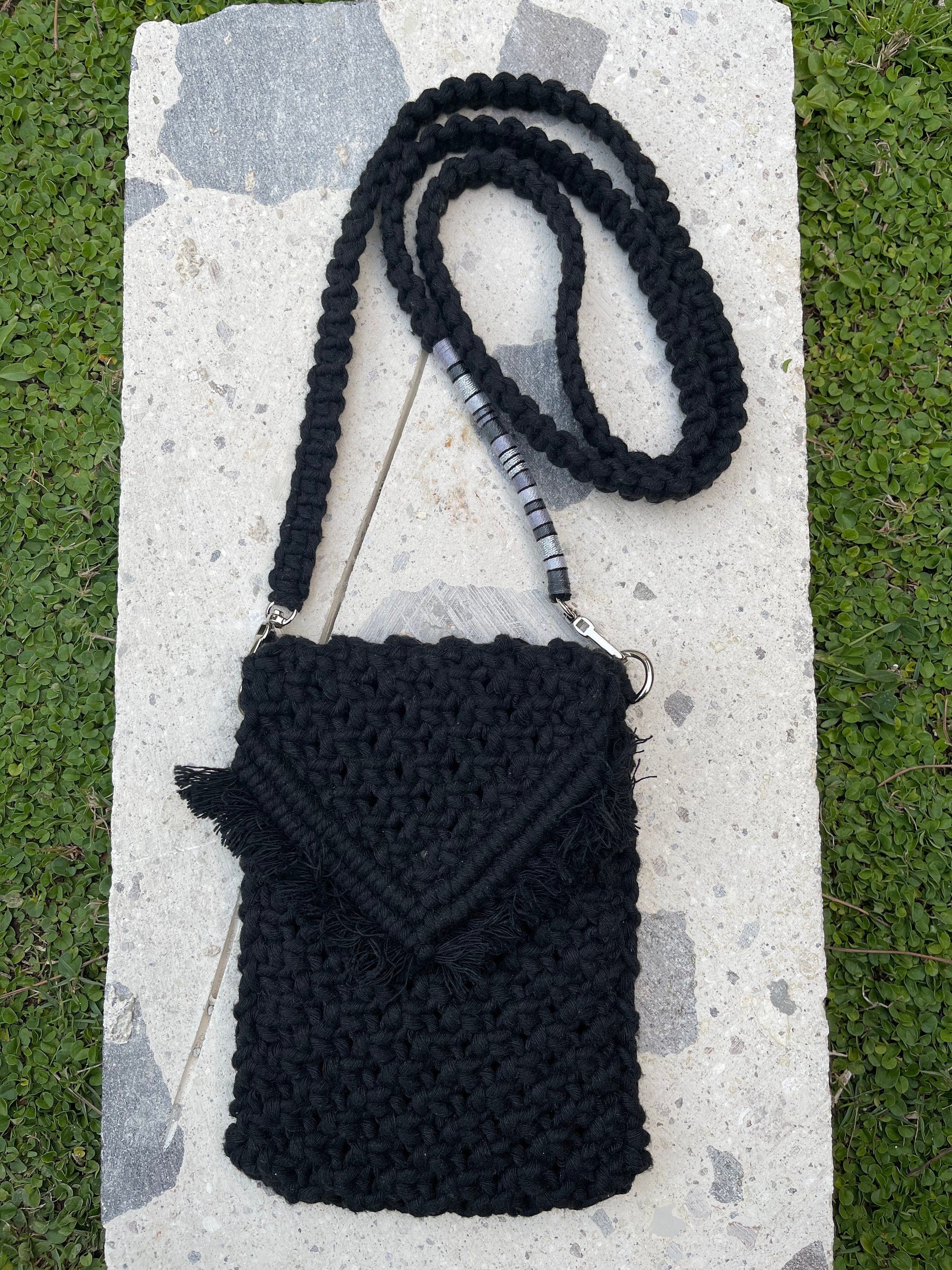 Black crocheted crossbody bag with a fringe detail and a long strap. The strap has a silver bead accent